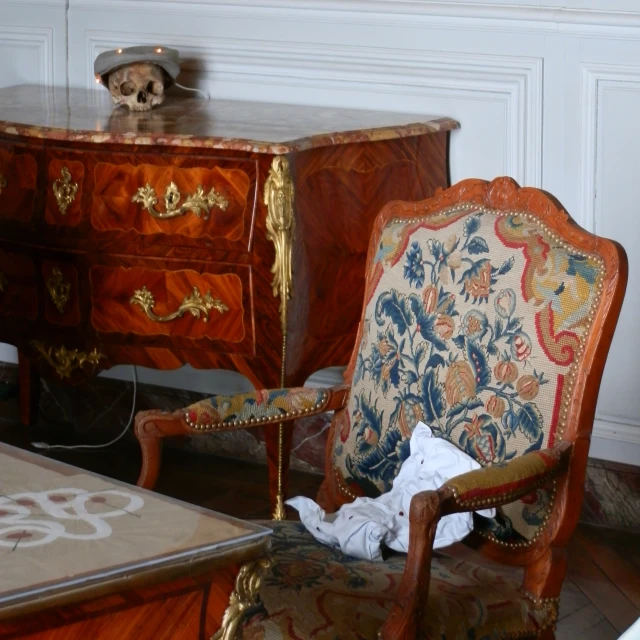 an ornate wooden chair and dresser in a room