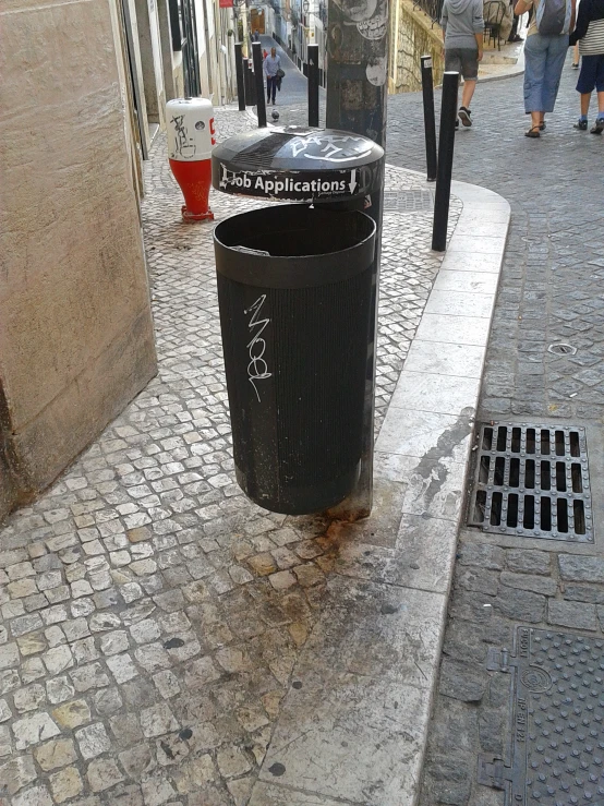 trash cans are on the edge of a narrow street