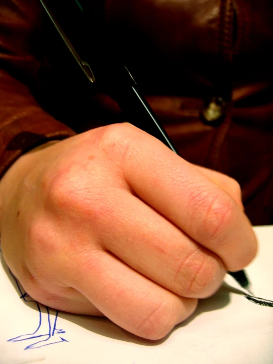 a person writing on paper with a pen