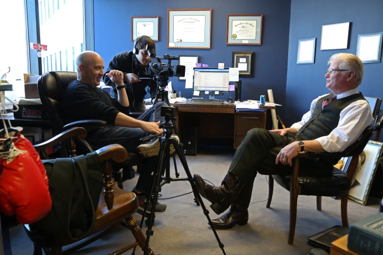 two men in a room while one of them is recording