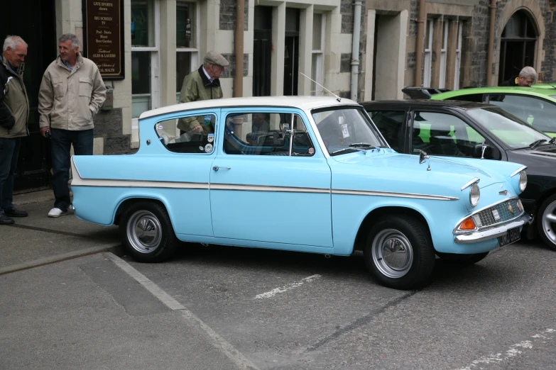 an old, light blue ford falcon station wagon parked on the street