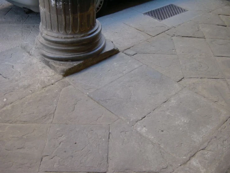 an empty sidewalk and stone walkway next to a pole