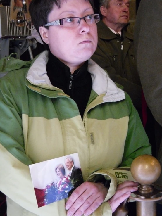 man with glasses holding picture and looking sad