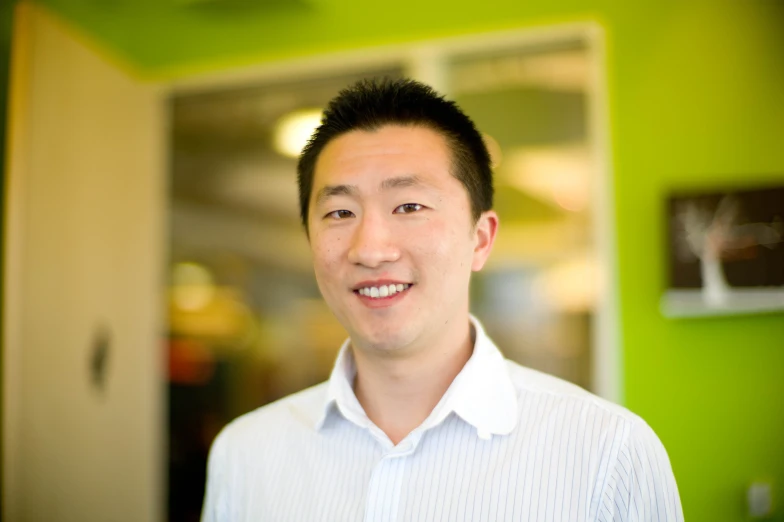 a man with black hair and blue shirt smiling