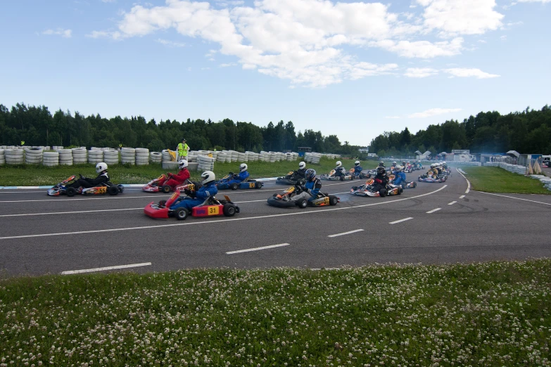 people racing cars on a road with trees in the background