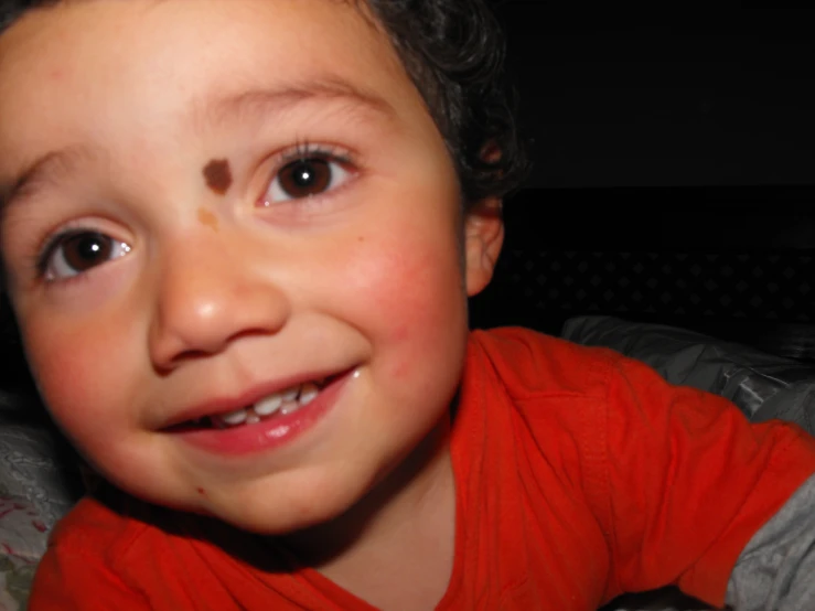 a small child in a red shirt and smiling