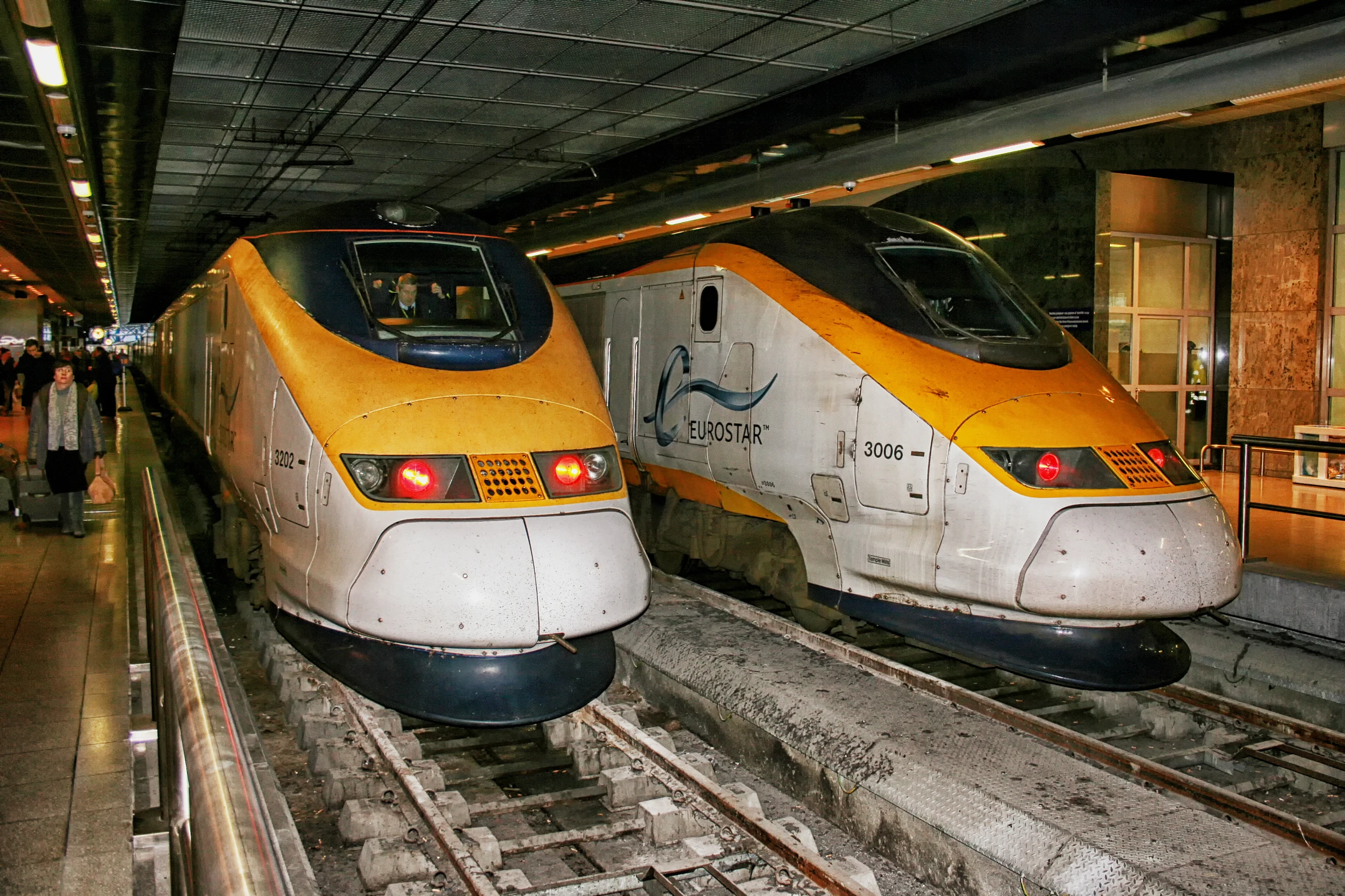 two yellow train cars sitting on train tracks in a train station