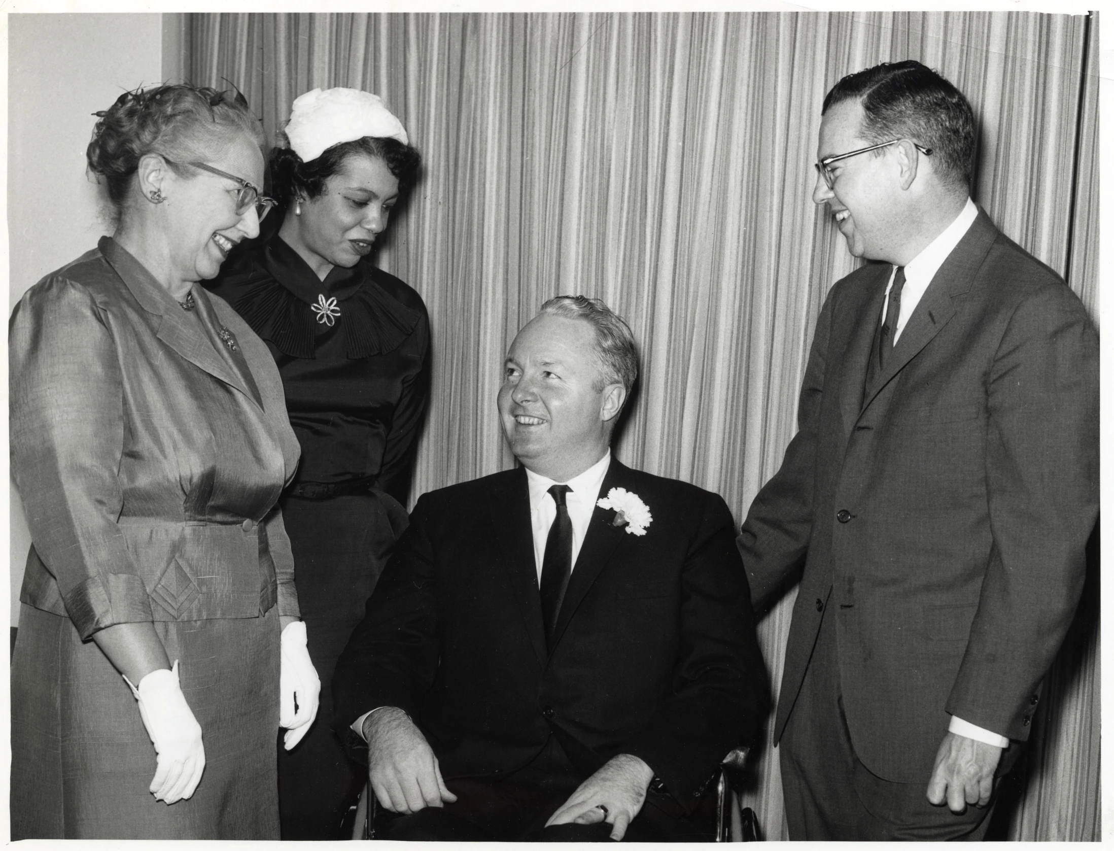 four people in suits and hats are standing and chatting