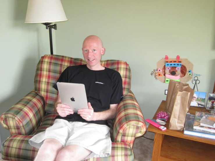 man sitting in plaid chair with ipad