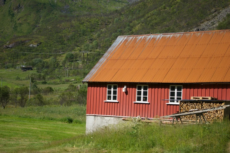 a red building with a brown roof in the green hills