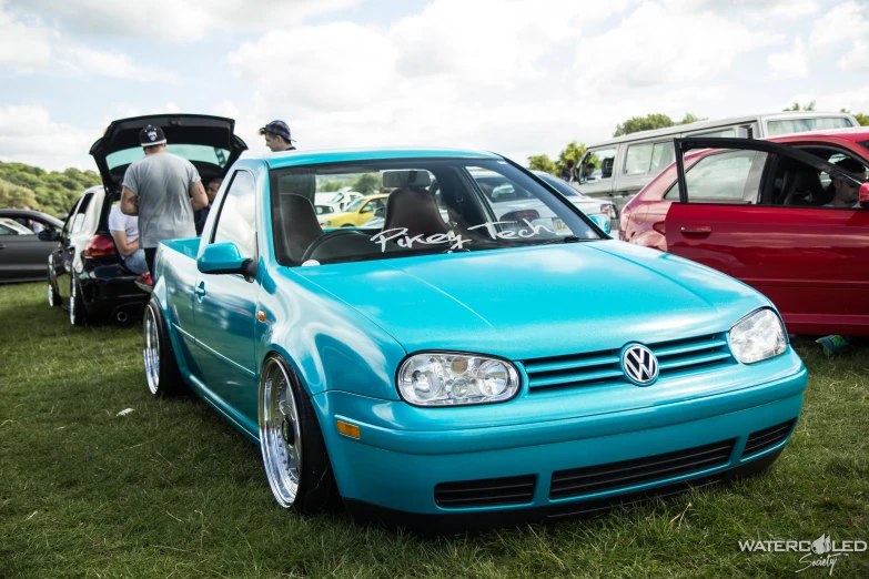 a car with some people around it parked on grass