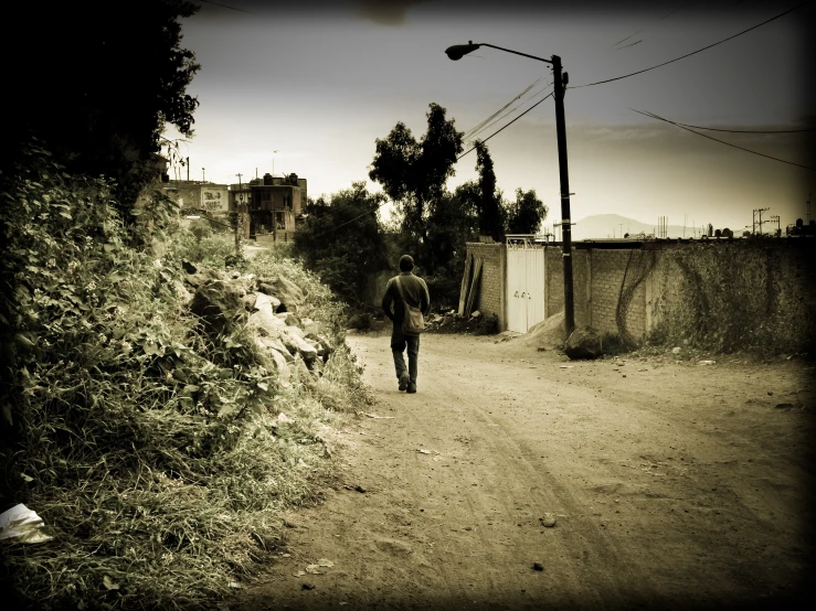 a man walking down a dirt road carrying a backpack
