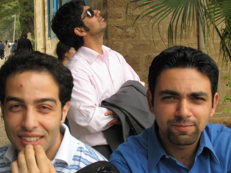 four men sitting on a curb with a building in the background