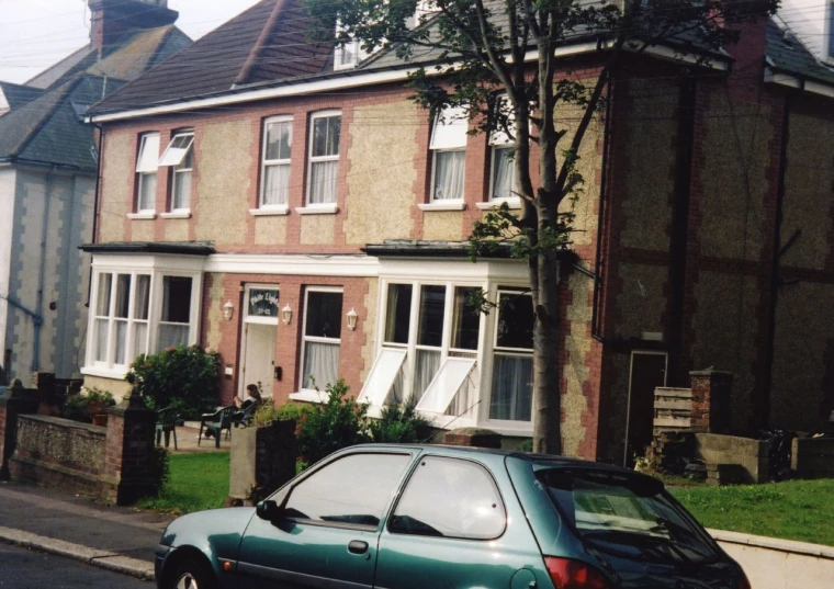 a car is parked in front of a house with broken windows