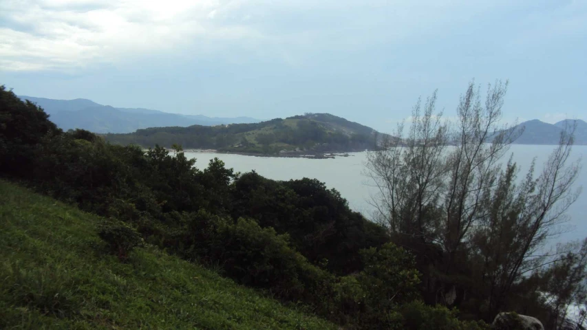 some small hills a body of water trees and grass