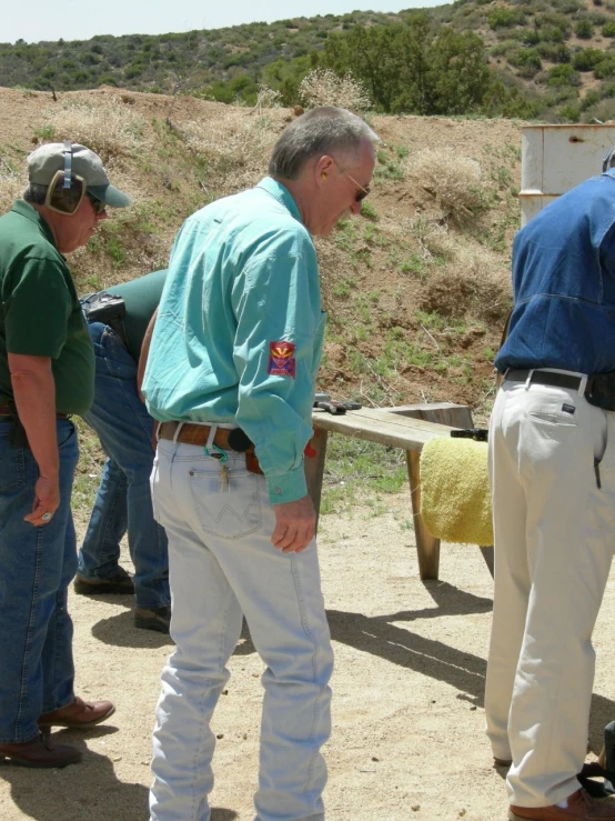 men standing around looking at soing with the man in a hat on his head