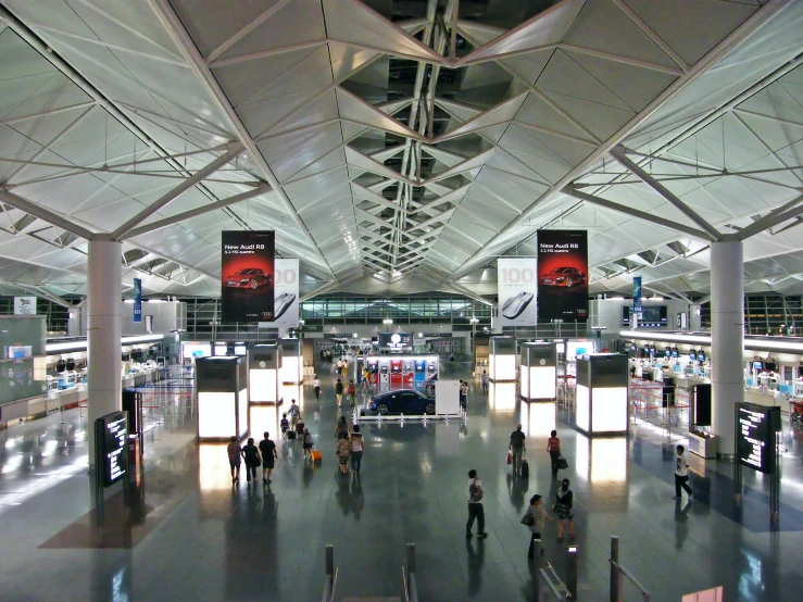 people walking around the airport and lobbys with multiple lights hanging overhead