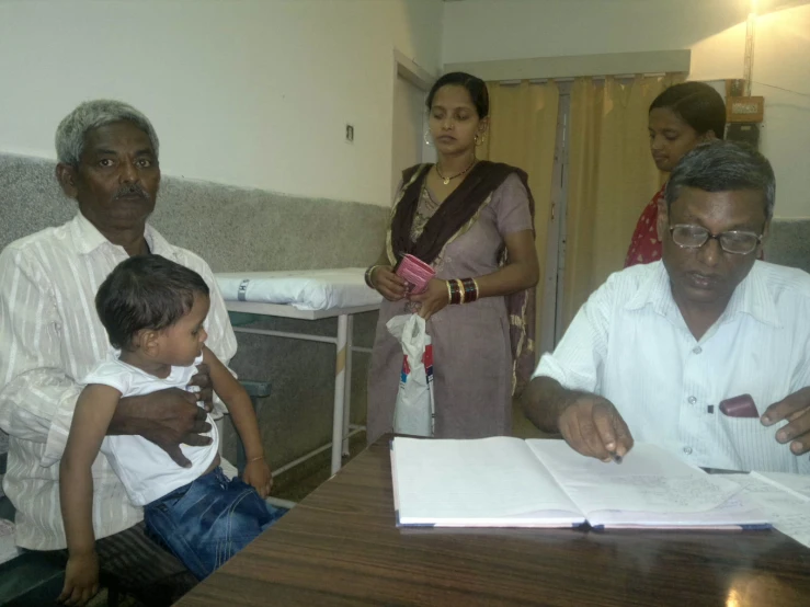 a man is holding a small child as they look over a book