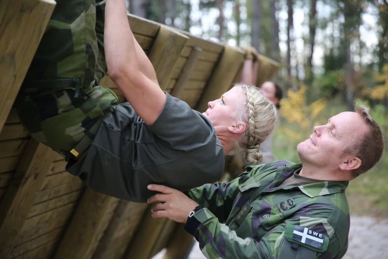 man in camouflage placing wood on large wooden bench