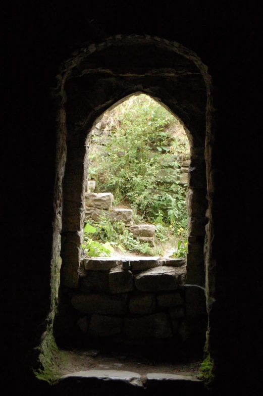 a stone arch doorway in the woods, showing a walkway