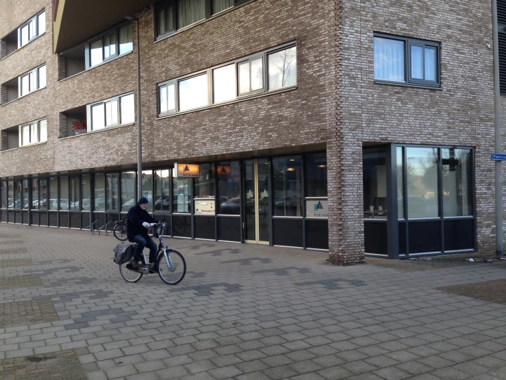 a man on a bike near a tall brick building