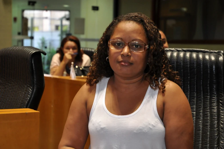 a woman with glasses at her desk next to some people