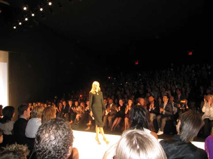 people watching a woman walking on the runway in front of an audience