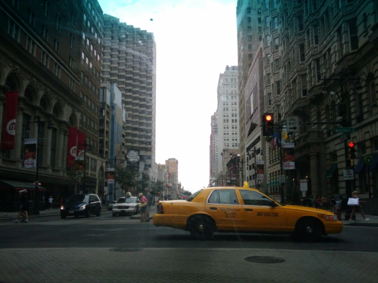 a yellow cab driving down a busy street surrounded by tall buildings