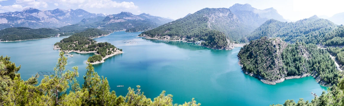 blue water surrounded by green mountains and evergreen trees