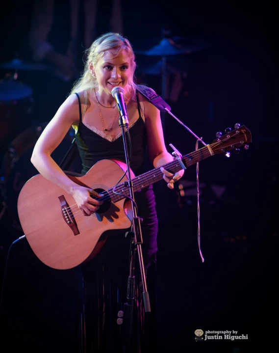 the girl is playing a guitar while singing