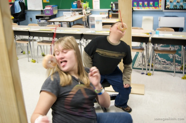 a girl laughing while sitting on a chair with a man