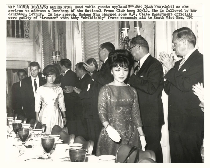 black and white po of women in formal attire next to a man and woman