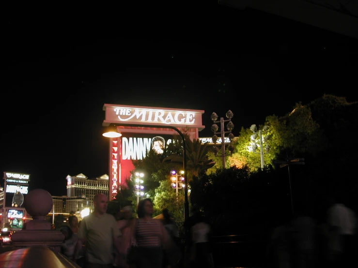 some people walking down a sidewalk and a large sign on a building