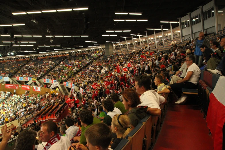 several people sit in rows at the end of an empty stadium