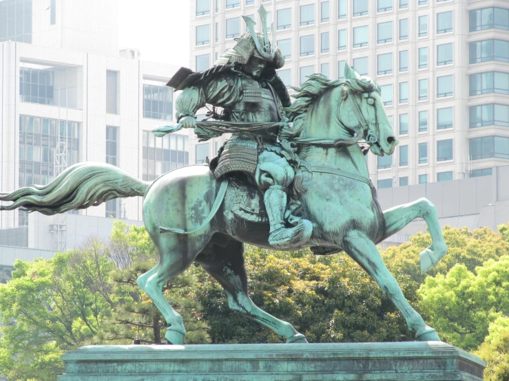 a statue of a man on a horse next to a skyscr