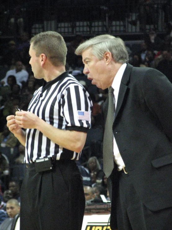 referee and man conversing during basketball game on court