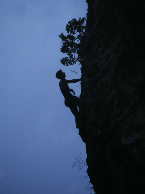 a man on the side of a cliff while he reaches up