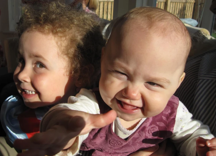 two small children sitting on the lap of their mothers