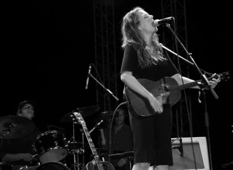 a woman singing with an electric guitar and drums