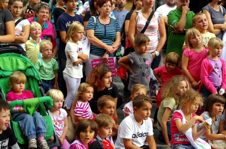 people stand behind a large group of toddlers and babies