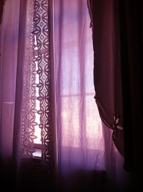 a window with sheer curtains and light coming through it