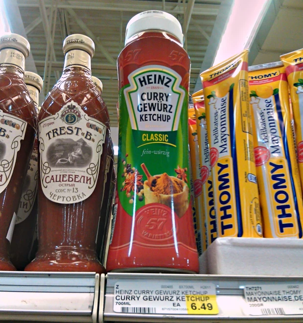 several bottles of ketchup sit on display with other foods