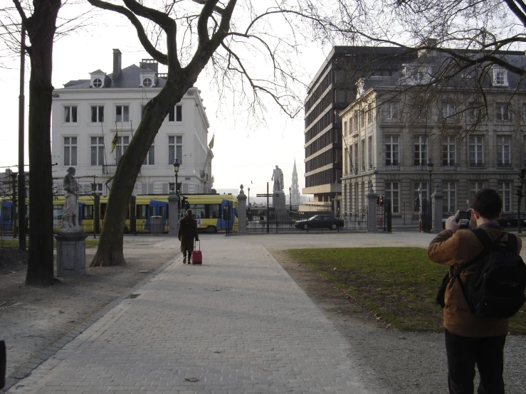 a woman in a jacket is standing near a yellow bus