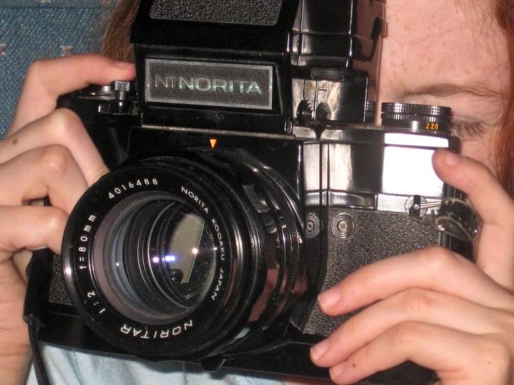 a young woman is holding a vintage camera