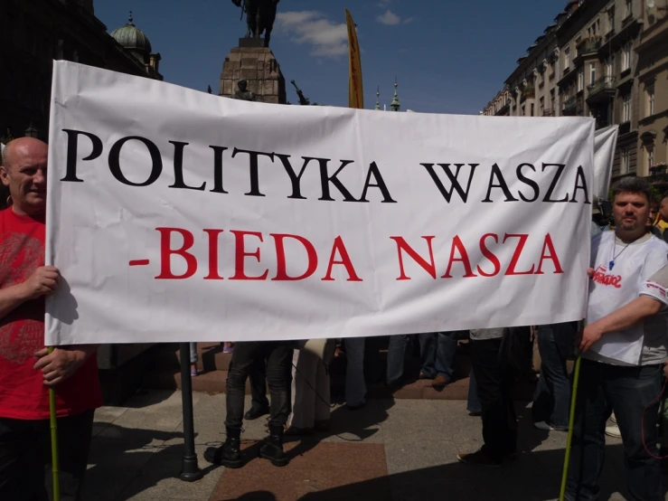 a person holding up a sign that reads polittya wasea - bieda nasza