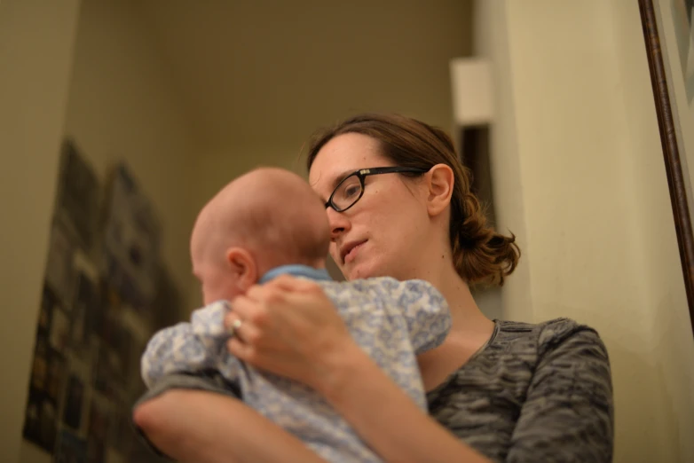 a woman with glasses is holding a baby