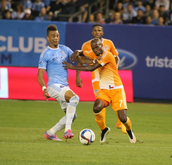 two soccer players going for the ball while two other players try to keep control