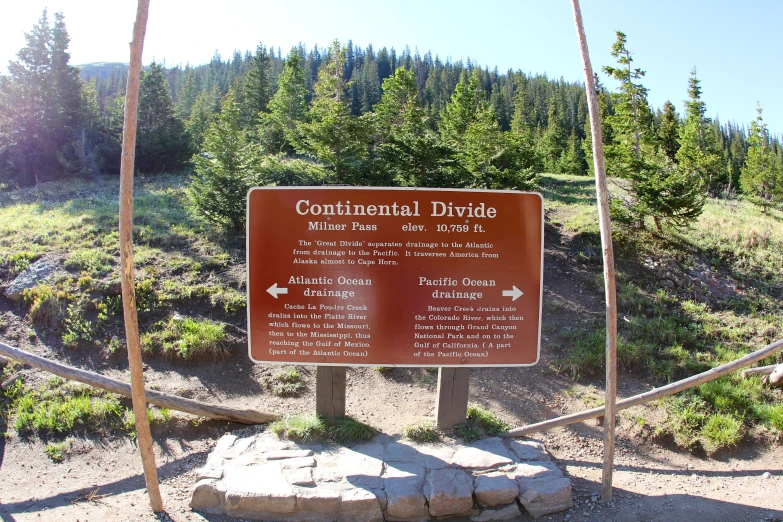 sign in front of some mountains warning hikers about continental divide