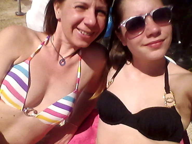 two young women are sitting on the beach