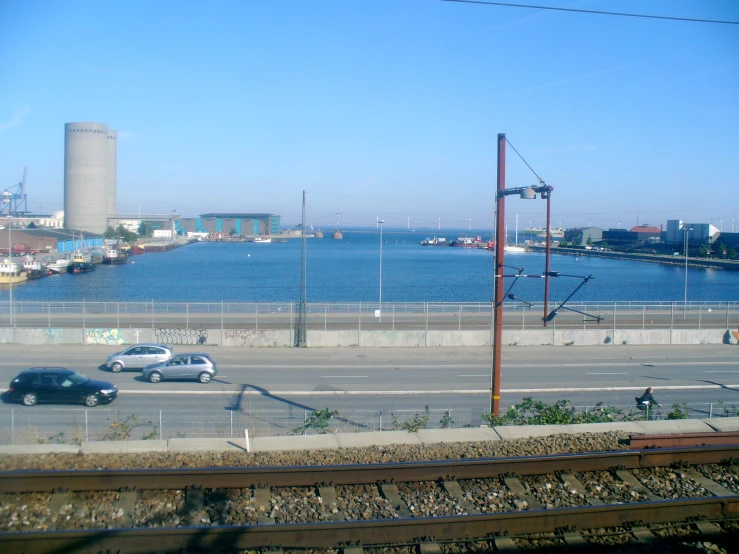 some cars driving down a street next to a body of water